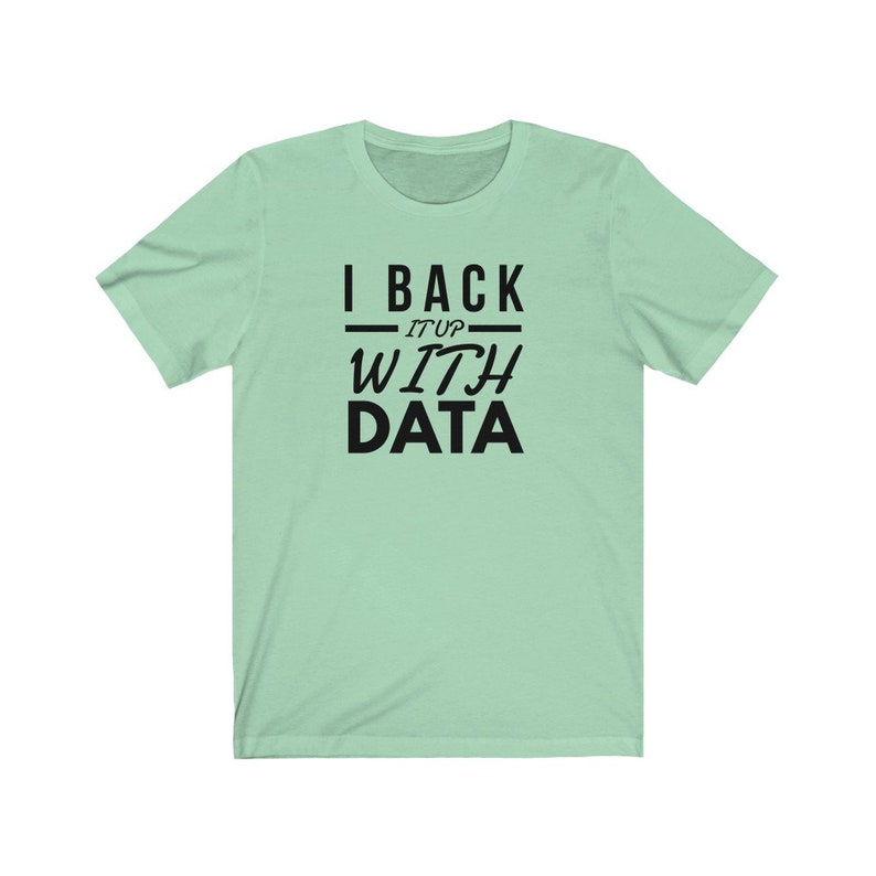 Puede incluir: Una camiseta de manga corta de color verde claro con texto negro impreso en el pecho que dice I BACK IT UP WITH DATA. La prenda tiene un cuello redondo y un corte est&aacute;ndar, mostrando un dise&ntilde;o gr&aacute;fico claro y legible en el centro.