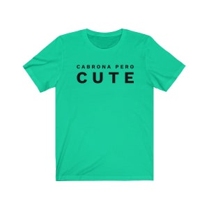 May include: A turquoise t-shirt with the text "Cabrona Pero Cute" printed in black.