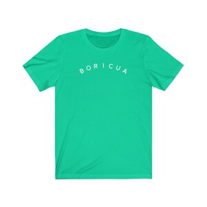 Puede incluir: Una camiseta verde brillante con la palabra "BORICUA" impresa en blanco en el pecho. La camiseta tiene mangas cortas y cuello redondo. El texto est&aacute; en una fuente sencilla, sin serifa.