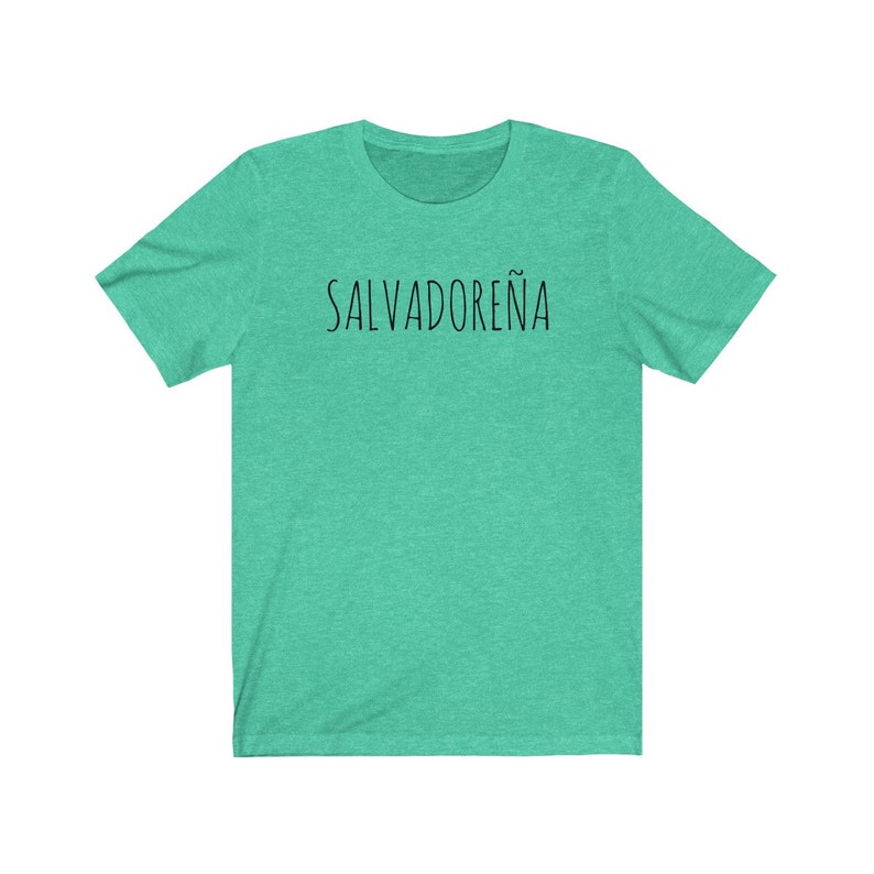 以下が含まれることがあります： 黒で「SALVADORE&Ntilde;A」とプリントされたターコイズグリーンのTシャツです。