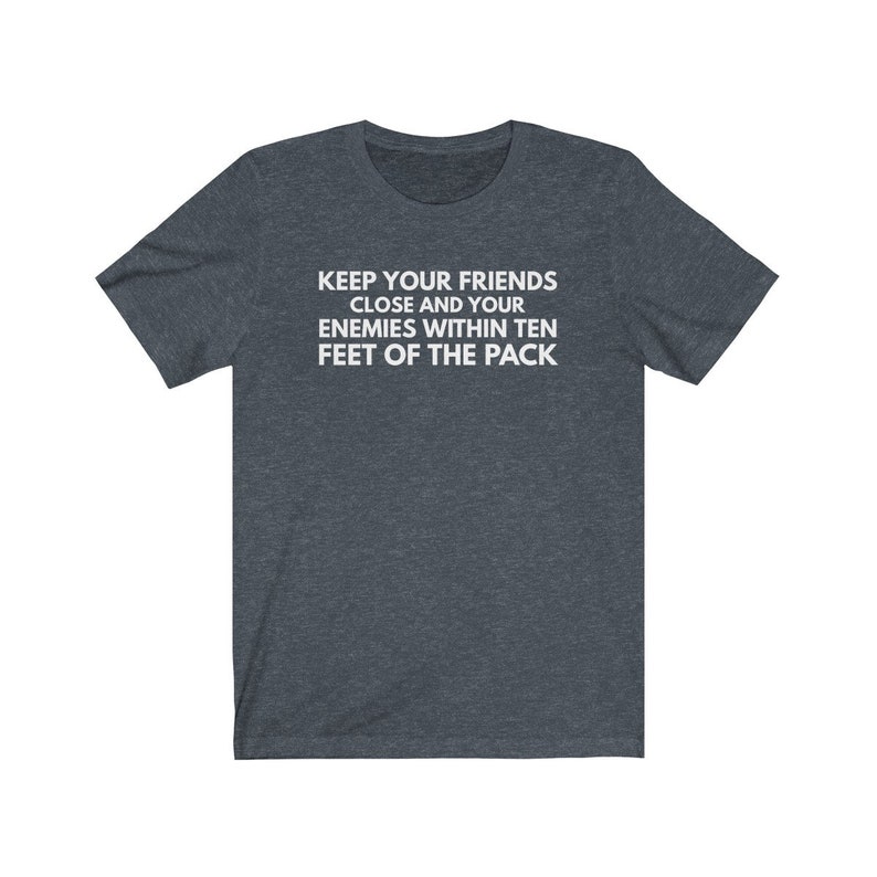 May include: A dark heather gray t-shirt with white text that reads "Keep your friends close and your enemies within ten feet of the pack."