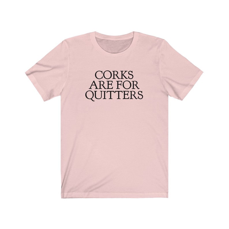 May include: A pink t-shirt with the text "Corks are for quitters" printed in black.