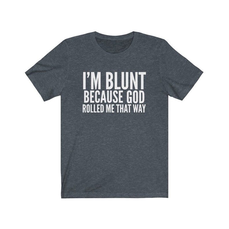 May include: Dark grey t-shirt with the white text "I'M BLUNT BECAUSE GOD ROLLED ME THAT WAY". The shirt has short sleeves and a crew neck. The text is centered on the front of the shirt.