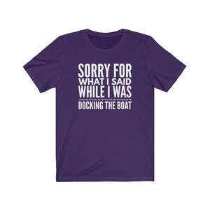 Op de afbeelding: Een paars t-shirt met de witte tekst "SORRY FOR WHAT I SAID WHILE I WAS DOCKING THE BOAT". Het shirt heeft korte mouwen en een ronde hals.