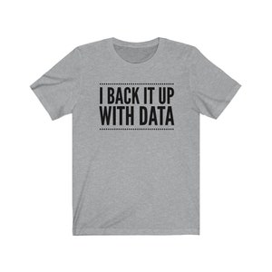 May include: A heather gray short-sleeve t-shirt featuring the black text I BACK IT UP WITH DATA centered on the chest. The text is enclosed between two horizontal lines made of small dots, creating a clean and simple graphic design on the shirt.