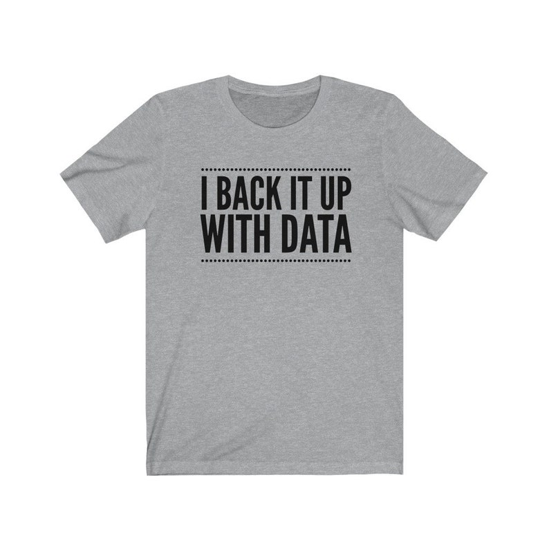 May include: A heather gray short-sleeve t-shirt featuring the black text I BACK IT UP WITH DATA centered on the chest. The text is enclosed between two horizontal lines made of small dots, creating a clean and simple graphic design on the shirt.