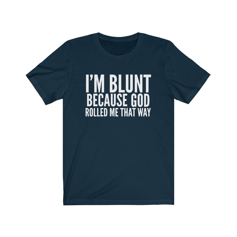 May include: Navy blue t-shirt with the white text "I'M BLUNT BECAUSE GOD ROLLED ME THAT WAY." The shirt has short sleeves and a crew neck. The text is centered on the front of the shirt.