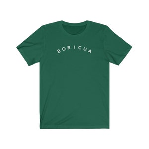 Puede incluir: Camiseta verde oscuro con la palabra "BORICUA" en blanco, arqueada sobre el pecho. La camiseta tiene mangas cortas y cuello redondo.