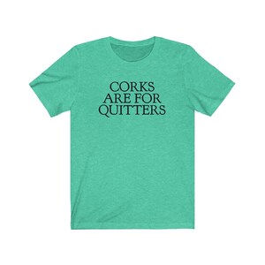 May include: A teal green t-shirt with the text "Corks Are For Quitters" printed in black.