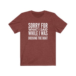 Op de afbeelding: Bordeauxrood t-shirt met de witte tekst "SORRY FOR WHAT I SAID WHILE I WAS DOCKING THE BOAT". Het shirt heeft korte mouwen en een ronde hals. De stof heeft een gem&ecirc;leerde textuur.