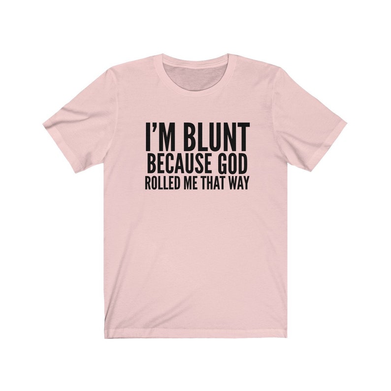 May include: A pink t-shirt with the text "I'M BLUNT BECAUSE GOD ROLLED ME THAT WAY" printed in black.