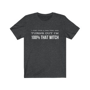 May include: A dark heather gray short-sleeve t-shirt with white text printed on the chest that reads: I JUST TOOK A DNA TEST AND TURNS OUT I'M 100% THAT WITCH. The shirt features a crew neckline and a standard fit with a simple, clean design.