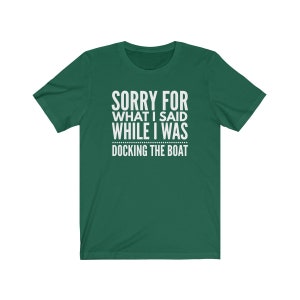 Op de afbeelding: Donkergroen t-shirt met witte tekst: "SORRY FOR WHAT I SAID WHILE I WAS DOCKING THE BOAT". Het shirt heeft korte mouwen en een ronde hals, geschikt voor casual wear.
