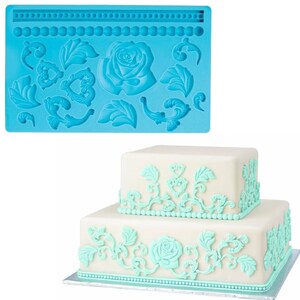 May include: A blue silicone mould with a rose, leaves, and scroll designs. The mould is used to create cake decorations. A two-tiered cake decorated with the designs from the mould is shown in the background.