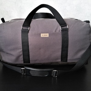 graue Reisetasche aus Canvas und Kunstleder, mit Reißverschlüssen und längenverstellbarem Tragegurt