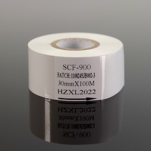May include: A white roll of thermal paper with black text on a label. The label reads "SCF-900", "BATCH: 1108245JB002-3", "30mmX100M", and "HZXL2022".