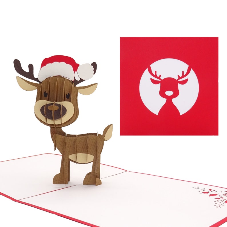 May include: A 3D pop-up card featuring a reindeer wearing a red and white Santa hat. The card is open and the reindeer is standing on a white background. The card has a red border and a small holly sprig in the bottom right corner.