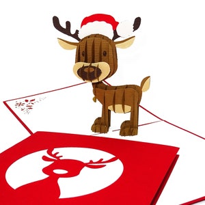 May include: A 3D pop-up Christmas card featuring a reindeer wearing a red Santa hat. The card is open and the reindeer is standing on a red background with a white reindeer silhouette.