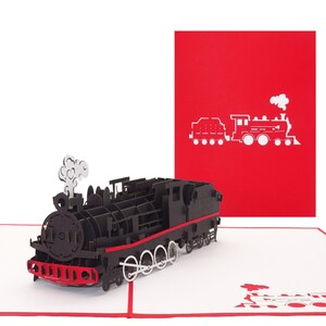 Puede incluir: Una tarjeta pop-up 3D negra y roja con un modelo detallado de un tren de vapor vintage. La tarjeta est&aacute; cerrada y muestra una silueta simple de un tren en la parte delantera.