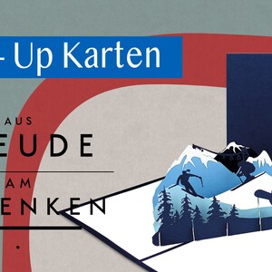 May include: A blue and white pop-up card with a winter mountain scene. The card is open and the pop-up features a mountain range with skiers and a ski lift. The card is from the company 'Freude am Schenken' and the text 'Pop-Up Karten' is at the top of the card.
