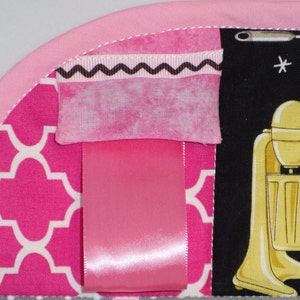 May include: Pink and white fabric with a geometric pattern. A pink ribbon is attached to the fabric. A pink and white fabric with a black zig-zag trim is attached to the fabric. A black and white fabric with a yellow mixer is attached to the fabric.