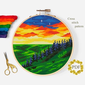 May include: Cross stitch pattern of a sunset over a forest with a blue sky and stars. The pattern is in a wooden embroidery hoop.