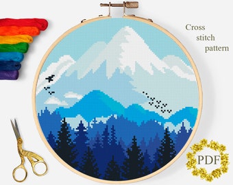 May include: Cross stitch pattern of a snowy mountain range with a forest in the foreground. The mountains are blue and white, and the forest is dark blue. There are birds flying in the sky.