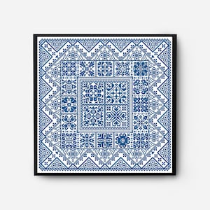 Op de afbeelding: Een ingelijst kruissteekpatroon met een geometrisch ontwerp in blauw en wit. Het patroon bestaat uit verschillende vierkanten en rechthoeken, elk met een ander ontwerp.