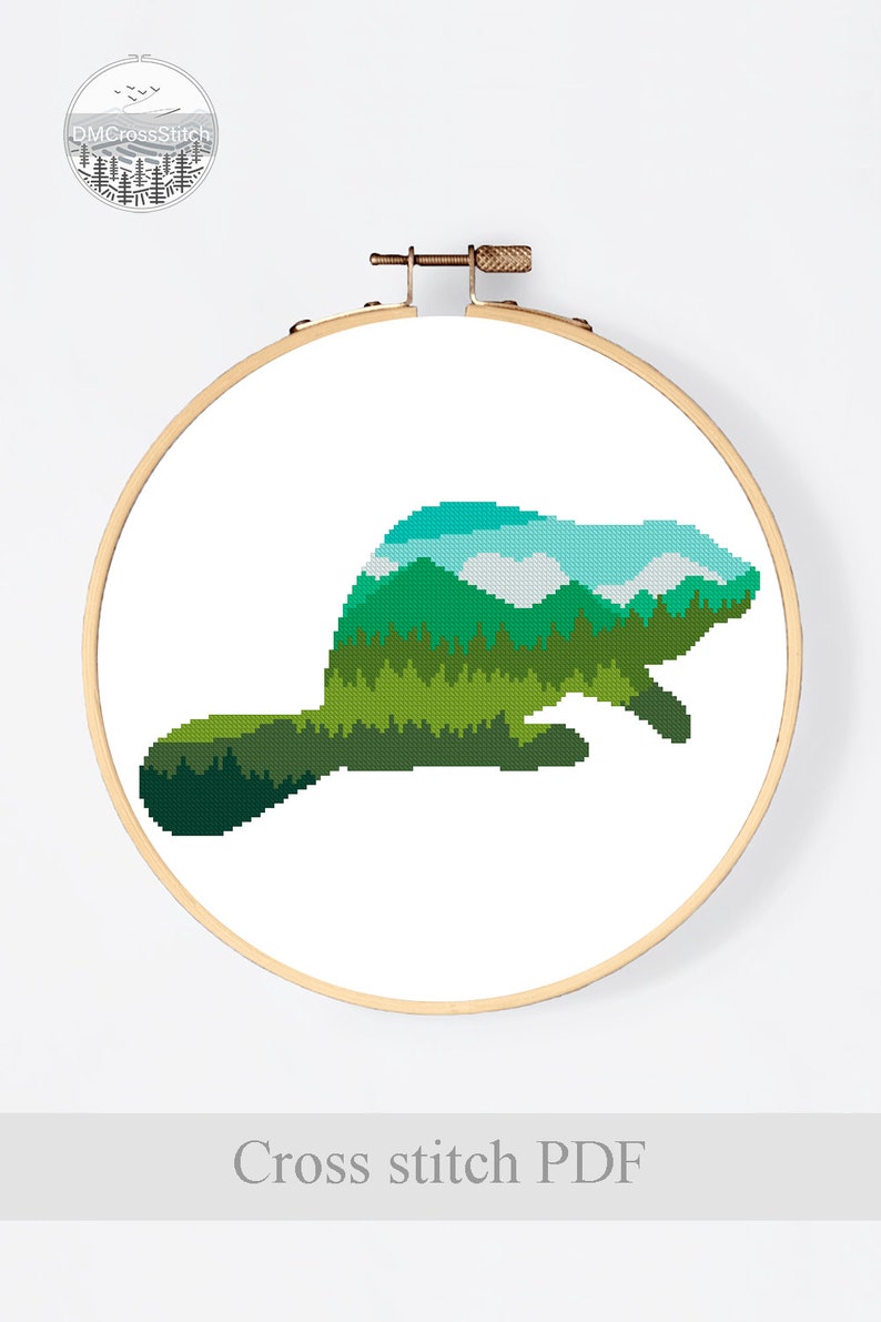 May include: Cross stitch pattern of a beaver silhouette filled with a green forest and blue sky landscape. The pattern is displayed in a wooden embroidery hoop. The text "Cross stitch PDF" is below the hoop.