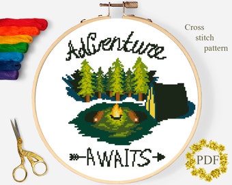 May include: Cross stitch pattern featuring a campfire scene with the text "Adventure Awaits". The design includes a campfire, trees, and a tent.