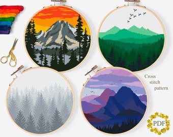 Puede incluir: Cuatro patrones de punto de cruz redondos con escenas de montañas y bosques. Cada diseño está enmarcado en un aro de madera. Las paletas de colores incluyen atardecer, verde, escala de grises y morado. El texto "Cross stitch pattern PDF" es visible.