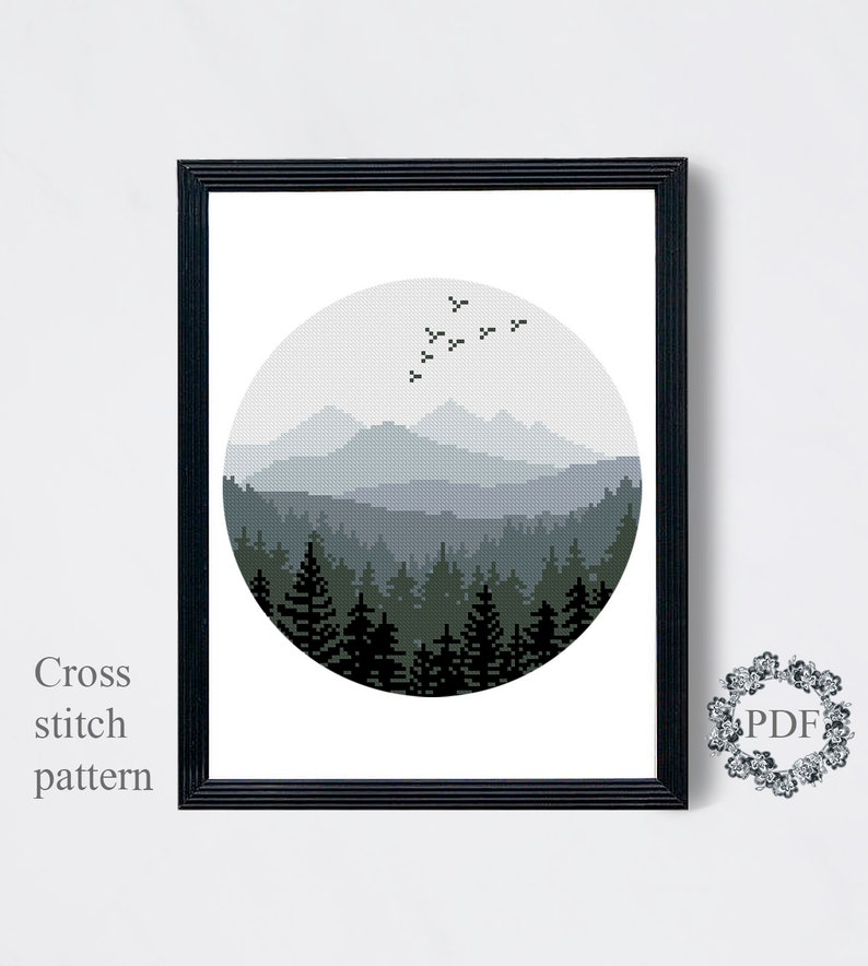 Peut inclure: Un motif de point de croix noir et blanc d'une for&ecirc;t et de montagnes dans un cercle. Les montagnes sont &agrave; l'arri&egrave;re-plan et la for&ecirc;t au premier plan. Il y a des oiseaux qui volent dans le ciel au-dessus des montagnes.