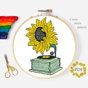 May include: Cross stitch pattern of a vintage record player with a sunflower on top. The record player is green and has a black record on it. The sunflower is yellow with a black center.