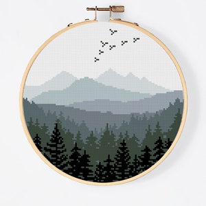 Peut inclure: Motif de point de croix repr&eacute;sentant une sc&egrave;ne de for&ecirc;t avec des montagnes en arri&egrave;re-plan. Les montagnes sont un d&eacute;grad&eacute; de bleu et de gris, et la for&ecirc;t est un d&eacute;grad&eacute; de vert et de noir. Il y a des oiseaux qui volent dans le ciel.
