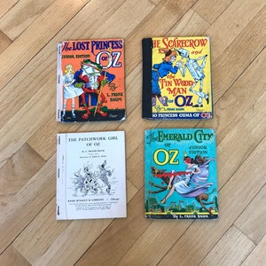 May include: Four vintage children's books featuring the "Oz" series by L. Frank Baum. The books are titled "The Lost Princess of Oz", "The Scarecrow and the Tin Woodman of Oz", "The Patchwork Girl of Oz", and "The Emerald City of Oz".