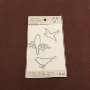 May include: A clear plastic packet containing three metal bird-shaped cutting templates. The templates are for paper crafting and are compatible with Sizzix, Cuttlebug, and Spellbinders machines. The package reads "CUTTING TEMPLATES" and "3 pc/pz".