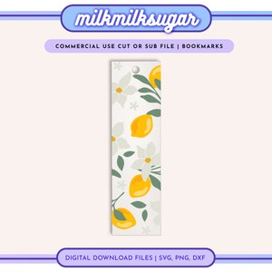 May include: A white bookmark with a lemon and white flower pattern. The bookmark has a hole at the top for a ribbon or string.