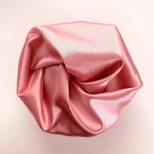 May include: A crumpled piece of soft, pink satin fabric.