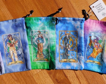 May include: Six tie-dye drawstring bags with different colorful designs. Each bag features a different tarot card illustration with a gold frame. The text on the tag reads "Artisan Oracle Bag of Holding".
