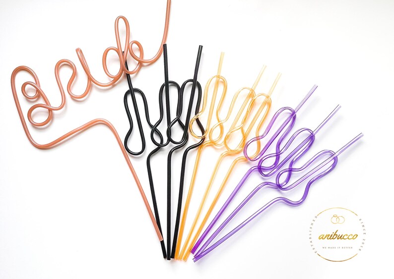 May include: A set of colorful reusable drinking straws shaped into different designs. The straws are pink, black, gold, and purple. The straws are bent into the shape of the word "bride" and the peace sign.