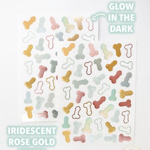 May include: A sheet of iridescent stickers featuring a repeating pattern of a single, stylized, anatomical heart shape. The stickers are in rose gold, silver, and gold colors. The text "Glow in the Dark" is written on the sheet. The text "Iridescent Rose Gold Silver Gold" is written below the sheet.