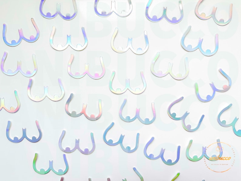 May include: A sheet of iridescent holographic stickers in the shape of breasts. The stickers are white with a rainbow sheen.