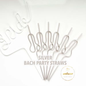 May include: An overhead shot shows a collection of silver and white party straws. The word "bride" is spelled out in white wire. The text "SILVER BACH PARTY STRAWS" is printed in silver. A gold logo is in the bottom right corner.