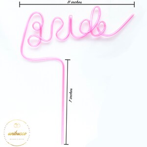 May include: Pink plastic straw shaped into the word "bride" with a 7 inch long straw attached. The straw is 11 inches wide.