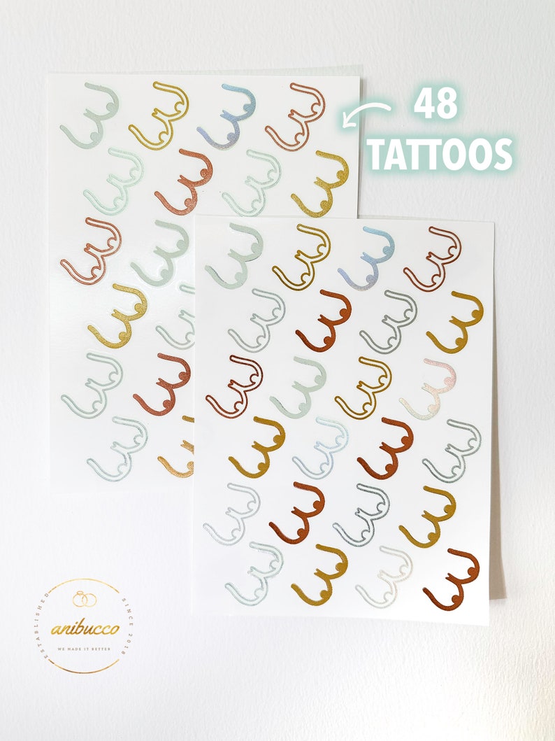 May include: Two sheets of temporary tattoos with 48 individual tattoos of a stylized breast shape in various colors, including gold, copper, and blue. The text "48 TATTOOS" is printed on the top of the image.