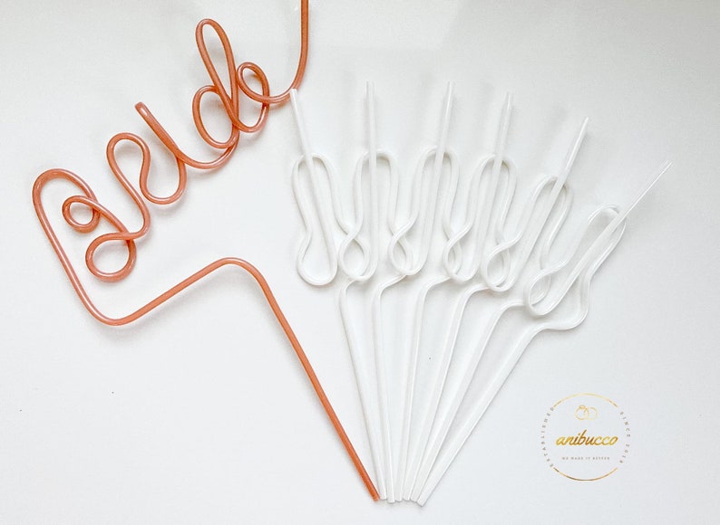 May include: A set of 10 white and one rose gold bendable straws. The rose gold straw is shaped to spell out the word "bride".