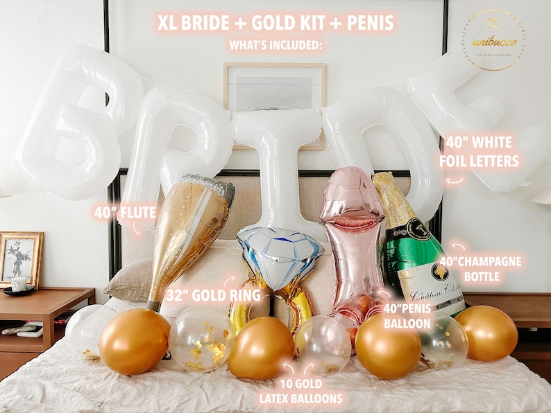 Extra large white letters spelling BRIDE hang above the bed in an arch. Below the letters on the bed rests 4 large foil balloons, a large flute, a gold ring, a green champagne bottle and 10 gold chrome and confetti filled balloons