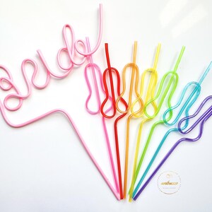 May include: A set of colorful, bendable drinking straws. The straws are arranged in a rainbow pattern, with the pink straw forming the word "bride".