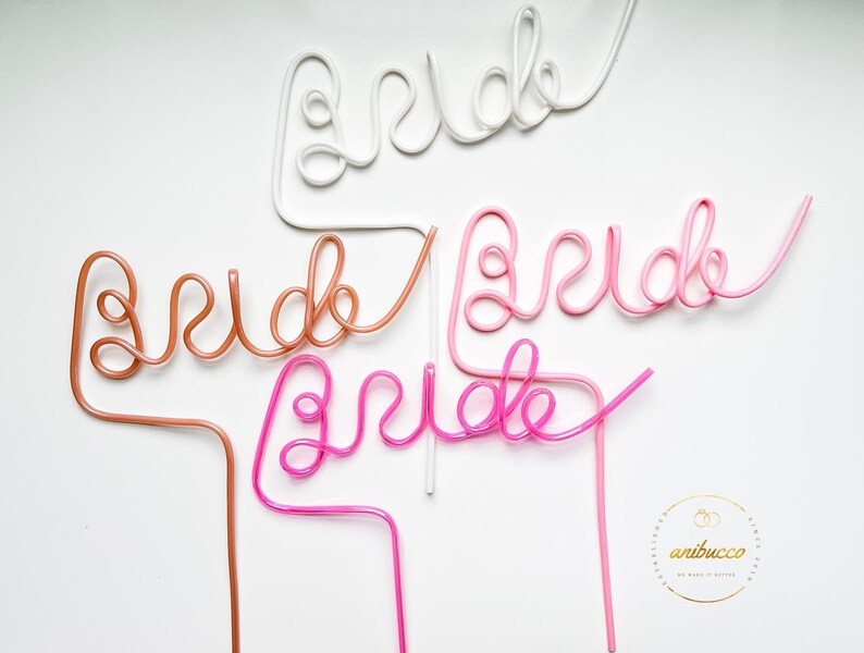 May include: Four plastic straws shaped to spell out the word "bride" in pink, white, and brown. The straws are on a white background.