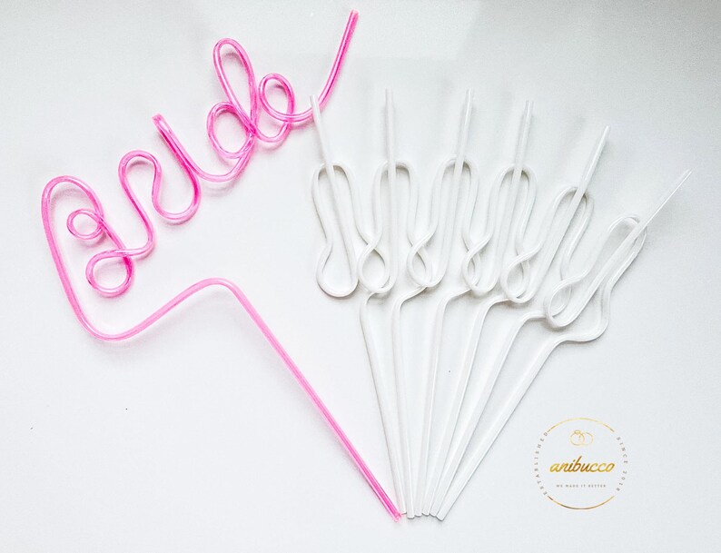 May include: Pink and white plastic straws shaped to spell "bride" and form a decorative design. The straws are on a white background.